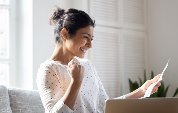 Woman rejoicing in home while looking at paper.